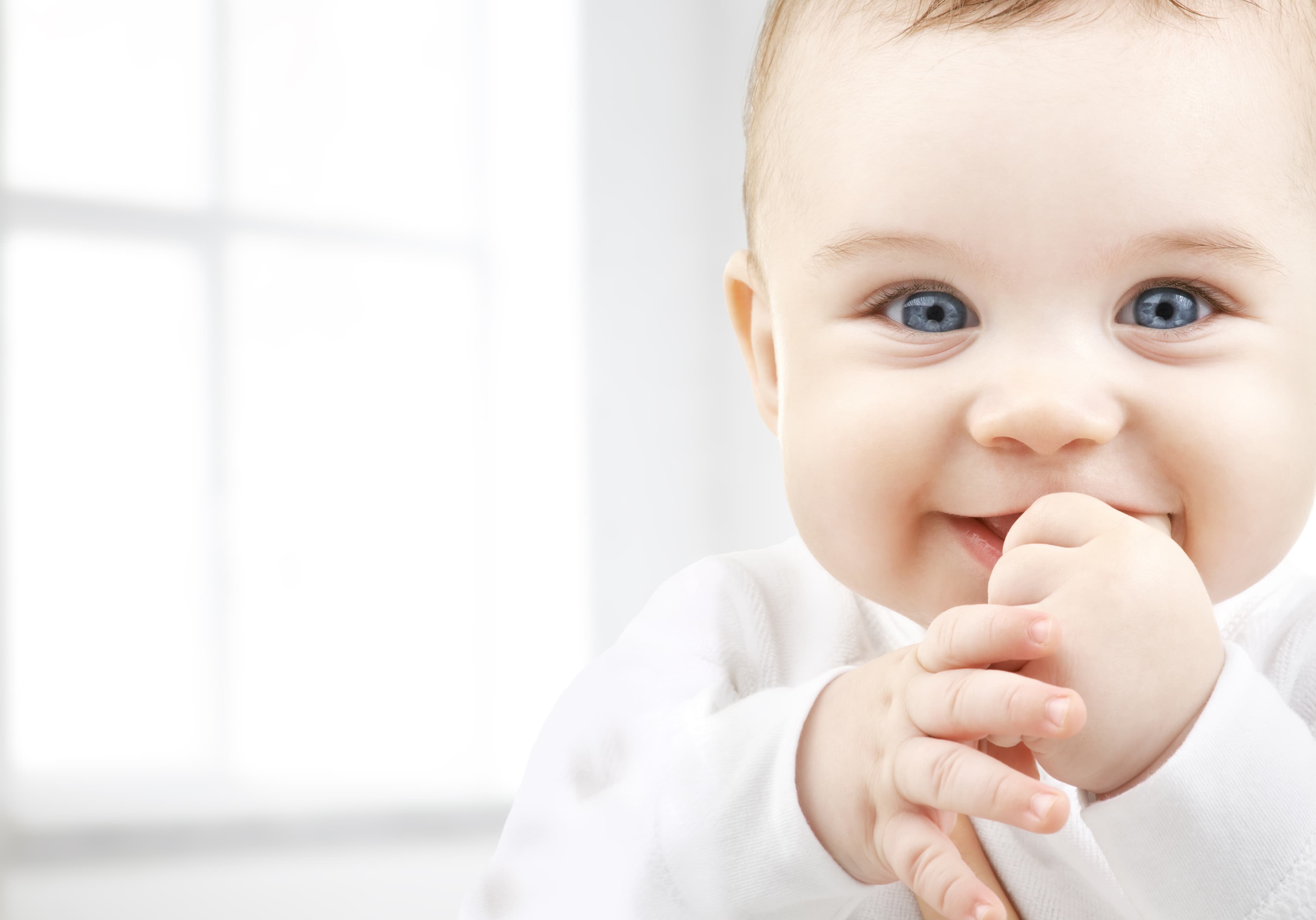 baby smiling and covering mouth with hands
