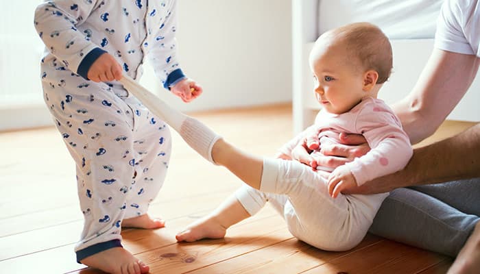 Father and toddler children sitting on the floor at home at bedtime.