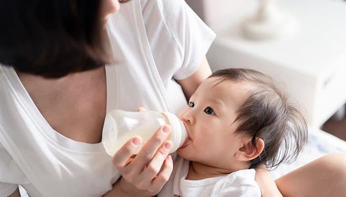mother giving baby bottle