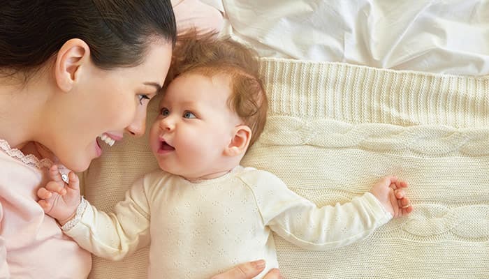 happy mother playing with her baby in the bedroom